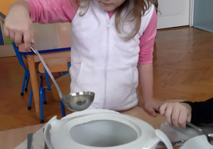 Kasia nalewa zupę z wazy na talerz.